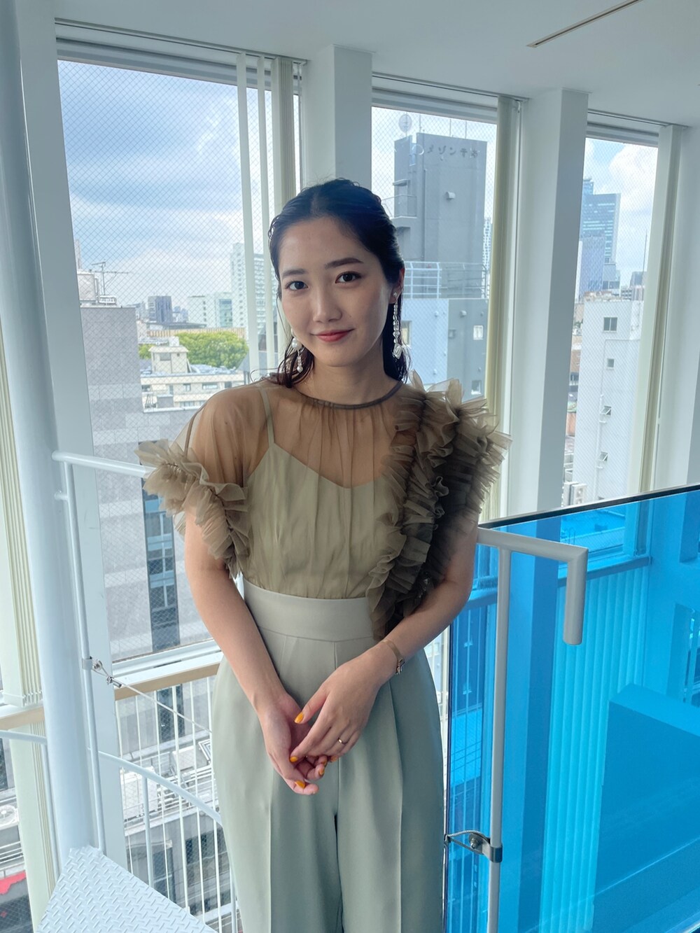 グリーン系のパンツドレス、ベージュ系のパンプスを着用したレディースの春コーディネートの6枚目の写真