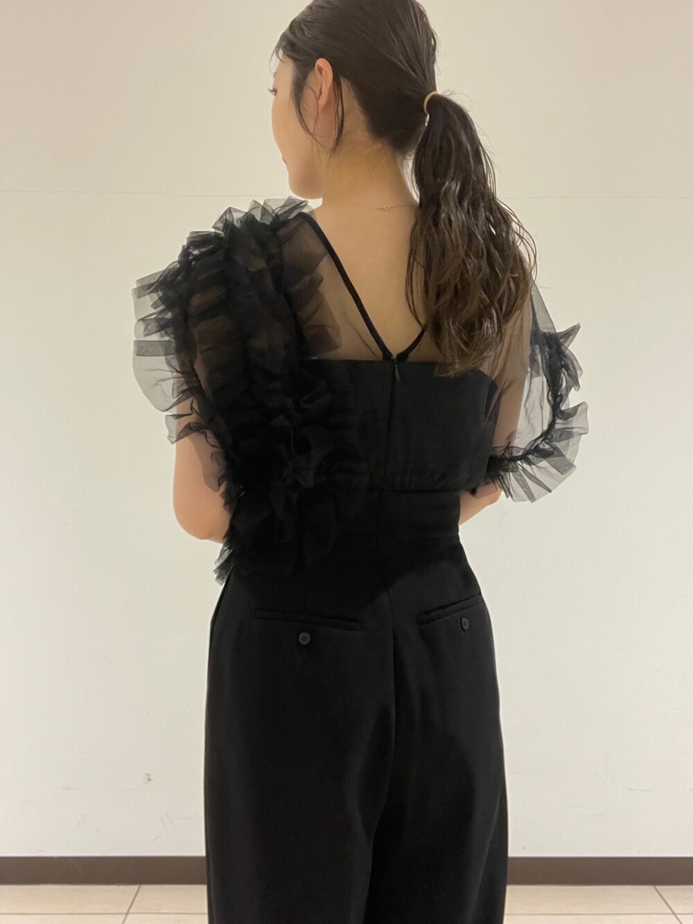 ブラック系のパンツドレス、シルバー系のクラッチバッグ、シルバー系のパンプスを着用したレディースの春コーディネートの9枚目の写真