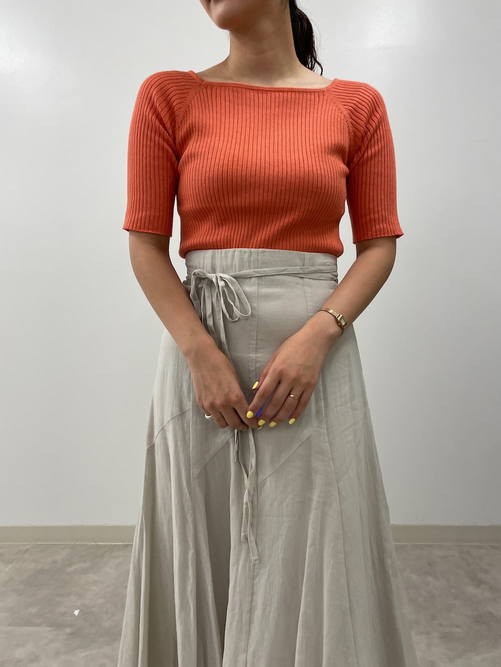 グレー系のスカート、ピンク系のニット/セーター、ブラック系のサンダルを着用したレディースの夏コーディネートの6枚目の写真