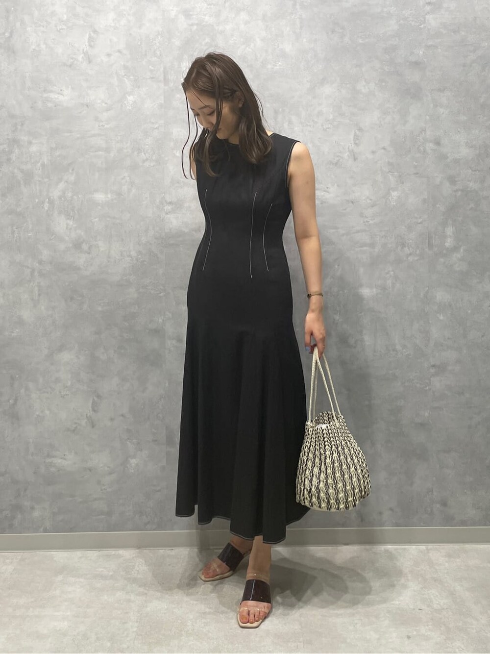 ブラウン系のサンダル、ホワイト系のハンドバッグ、ブラック系のワンピースを着用したレディースの夏コーディネートの4枚目の写真