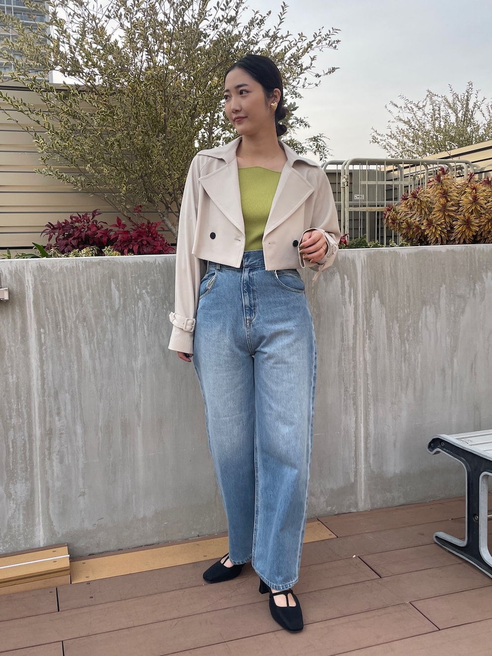 ブルー系のデニムパンツ、ホワイト系のトレンチコート、グリーン系のニット/セーターを着用したレディースの冬コーディネートの2枚目の写真