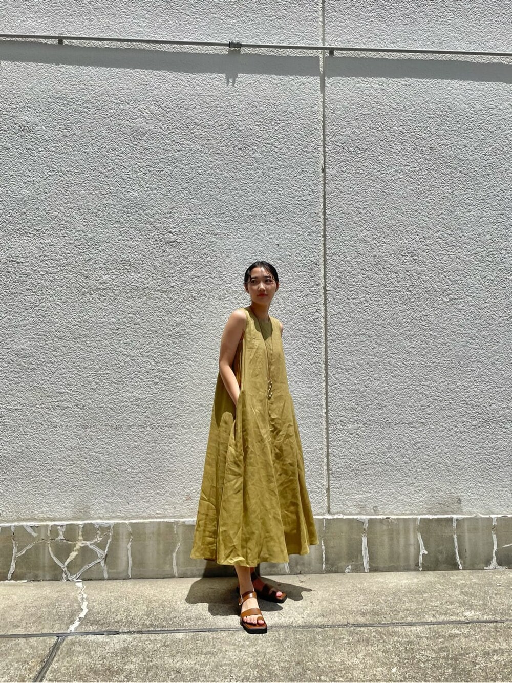 ブラウン系のサンダル、グリーン系のワンピース、ゴールド系のネックレスを着用したレディースの夏コーディネートの2枚目の写真