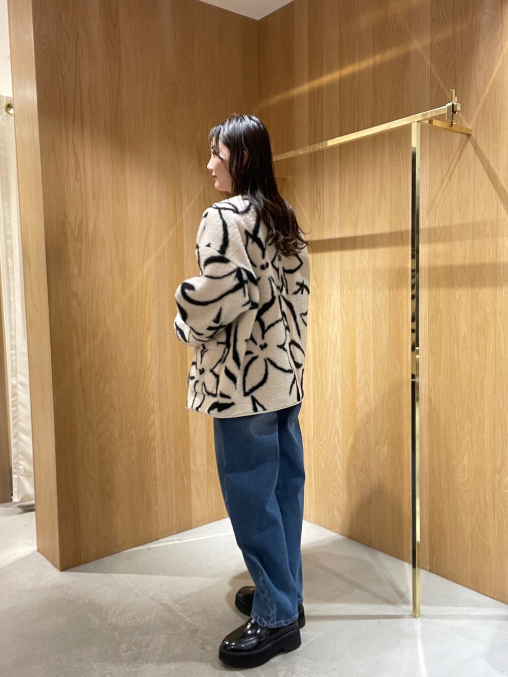 ブルー系のデニムパンツ、ホワイト系のブルゾン、グリーン系のニット/セーターを着用したレディースの秋コーディネートの2枚目の写真