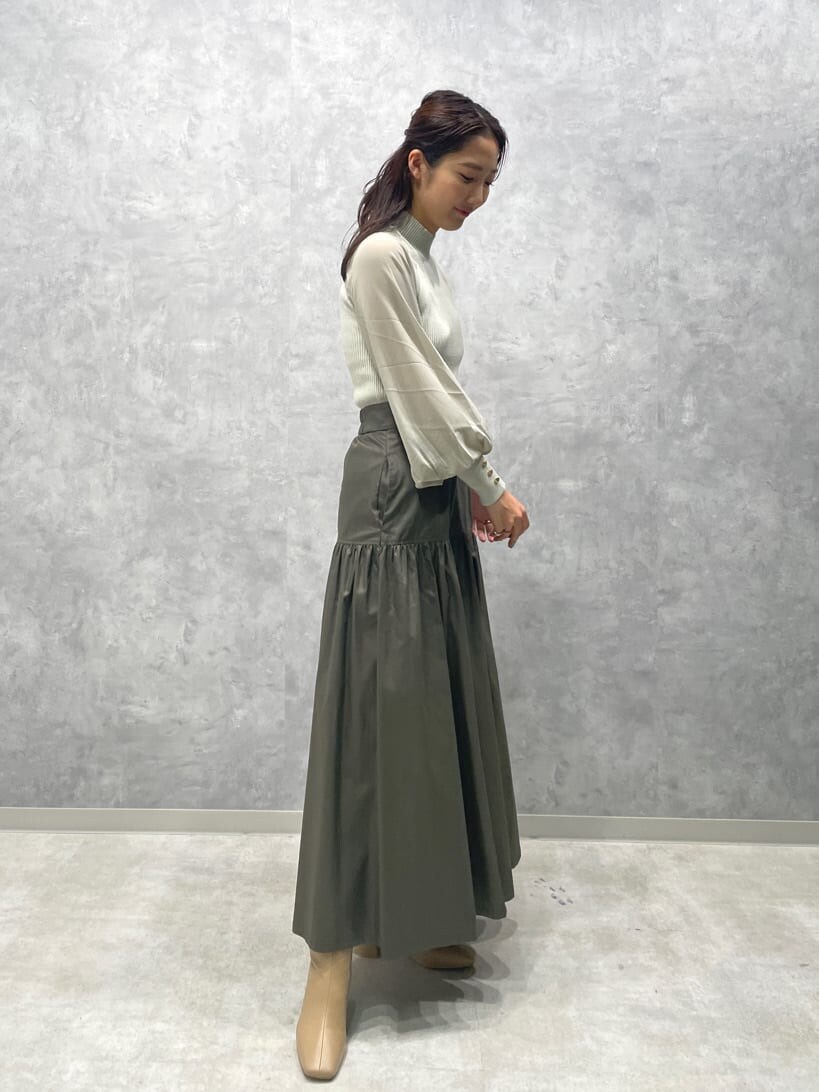 ベージュ系のスカート、ベージュ系のブーツ、グリーン系のニット/セーターを着用したレディースの夏コーディネートの4枚目の写真