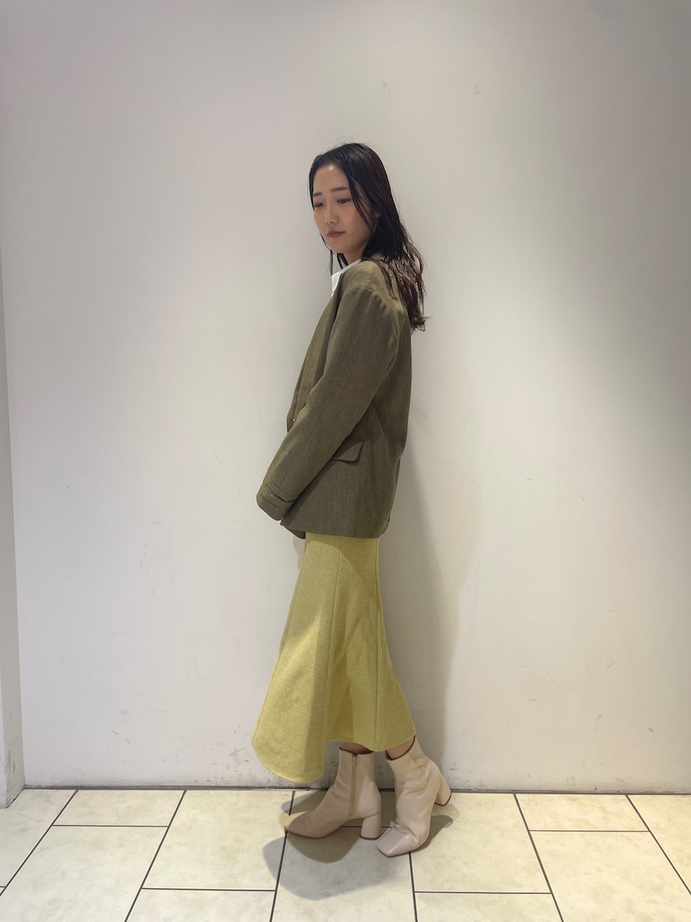 イエロー系のワンピース、ホワイト系のブーツ、ブラウン系のテーラードジャケットを着用したレディースの秋コーディネートの4枚目の写真