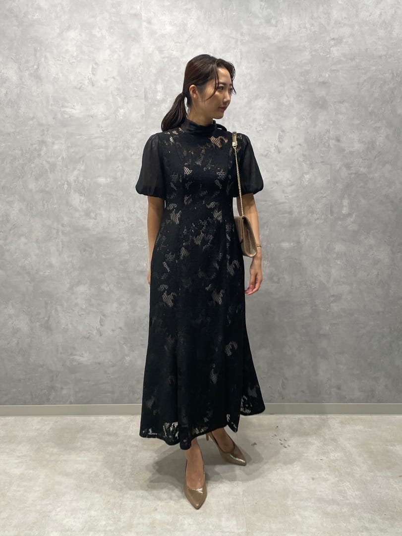 ゴールド系のパンプス、ゴールド系のクラッチバッグ、ブラック系のドレスを着用したレディースの秋コーディネートの2枚目の写真