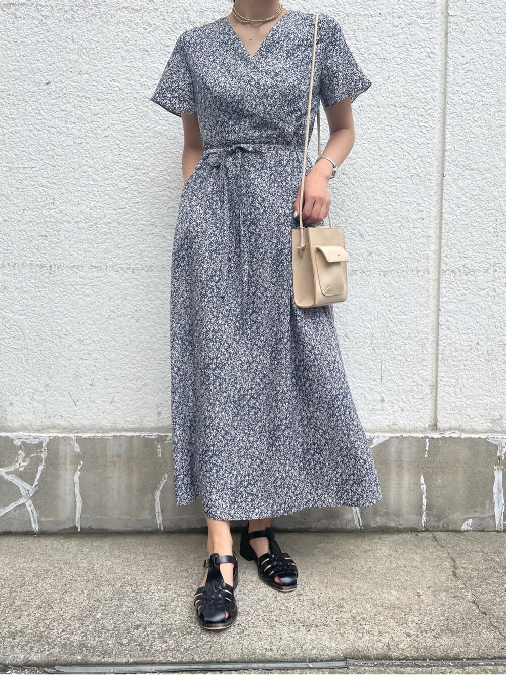 ベージュ系のハンドバッグ、ブルー系のワンピース、ゴールド系のネックレスを着用したレディースの夏コーディネートの3枚目の写真