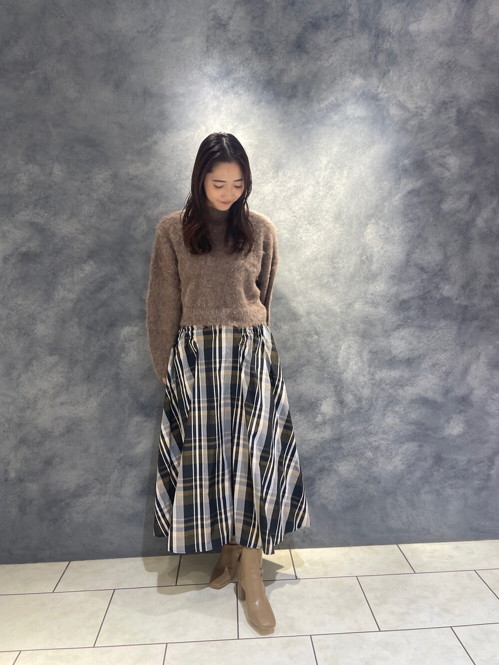 ブラウン系のニット/セーター、オレンジ系のスカート、ベージュ系のブーツを着用したレディースの秋コーディネートの7枚目の写真