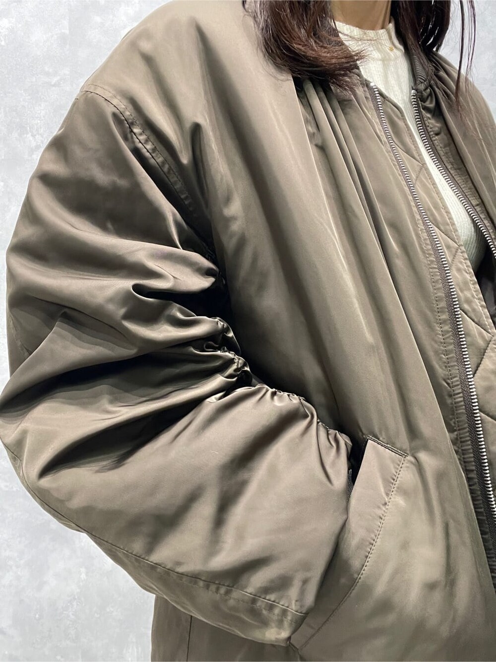 ベージュ系のブーツ、ホワイト系のニット/セーター、ブラウン系のMA-1を着用したレディースの秋コーディネートの8枚目の写真