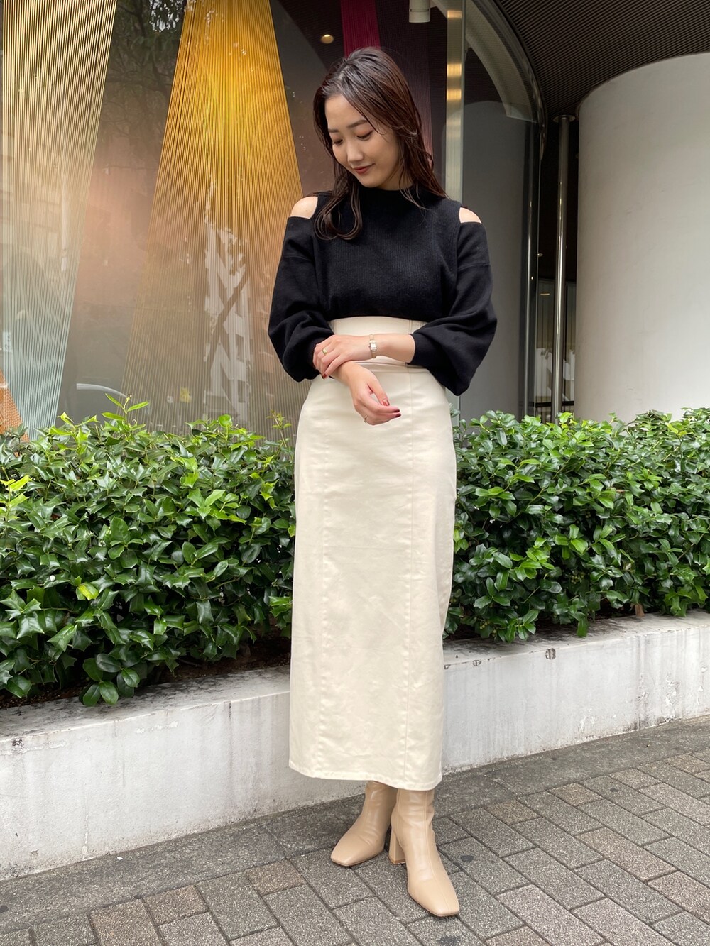 ベージュ系のブーツ、ブラック系のニット/セーター、ホワイト系のスカートを着用したレディースの秋コーディネートの2枚目の写真