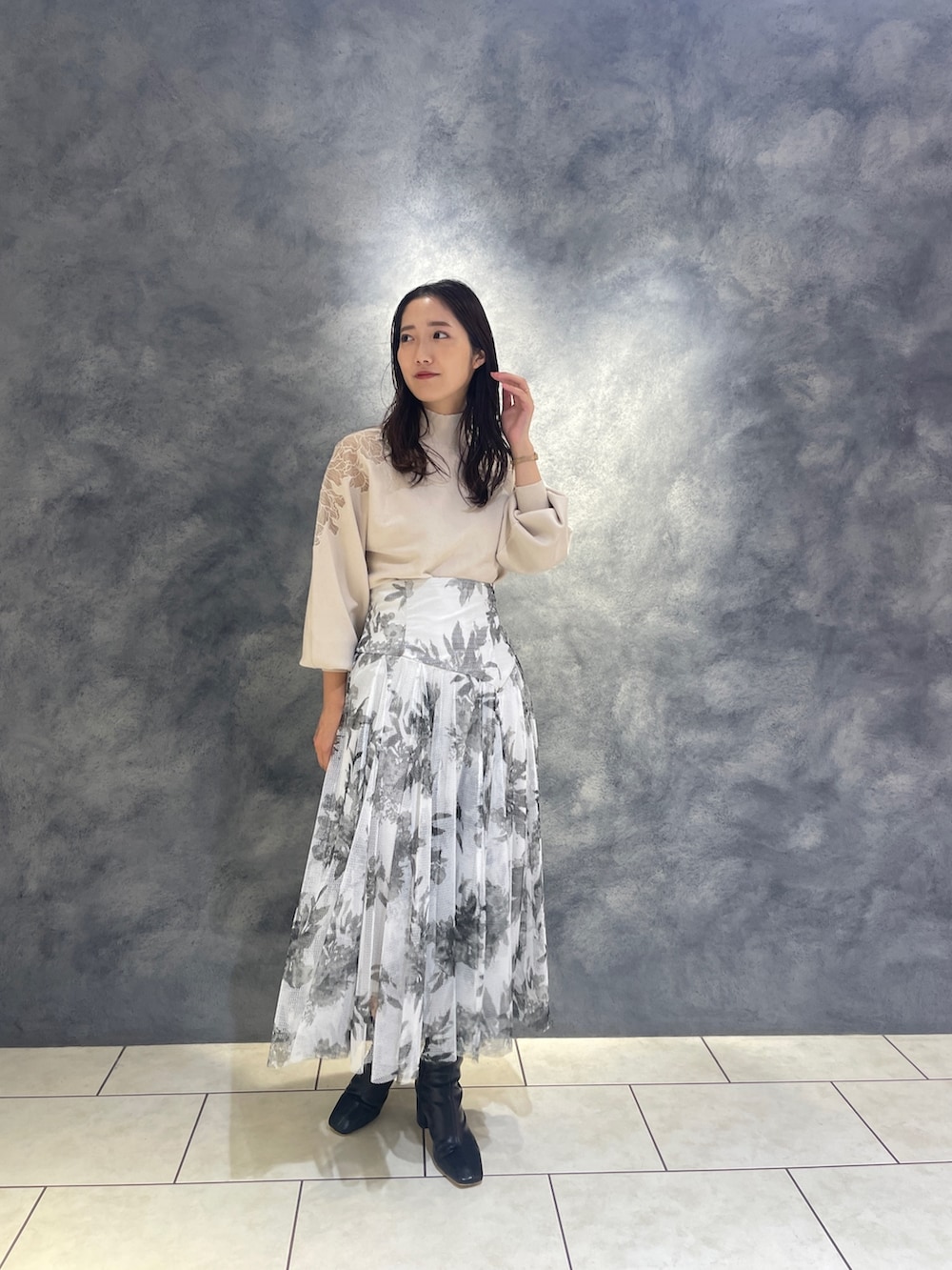 ホワイト系のニット/セーター、ブラック系のブーツ、ブラック系のスカートを着用したレディースの秋コーディネートの3枚目の写真