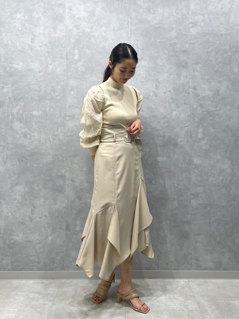 ベージュ系のサンダル、ホワイト系のニット/セーター、ホワイト系のスカートを着用したレディースの冬コーディネートの3枚目の写真