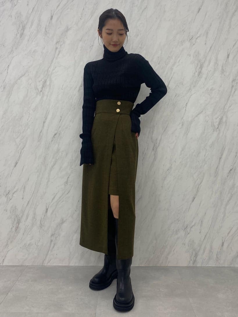 ベージュ系のスカート、ブラック系のニット/セーター、ブラック系のブーツを着用したレディースの夏コーディネートの4枚目の写真