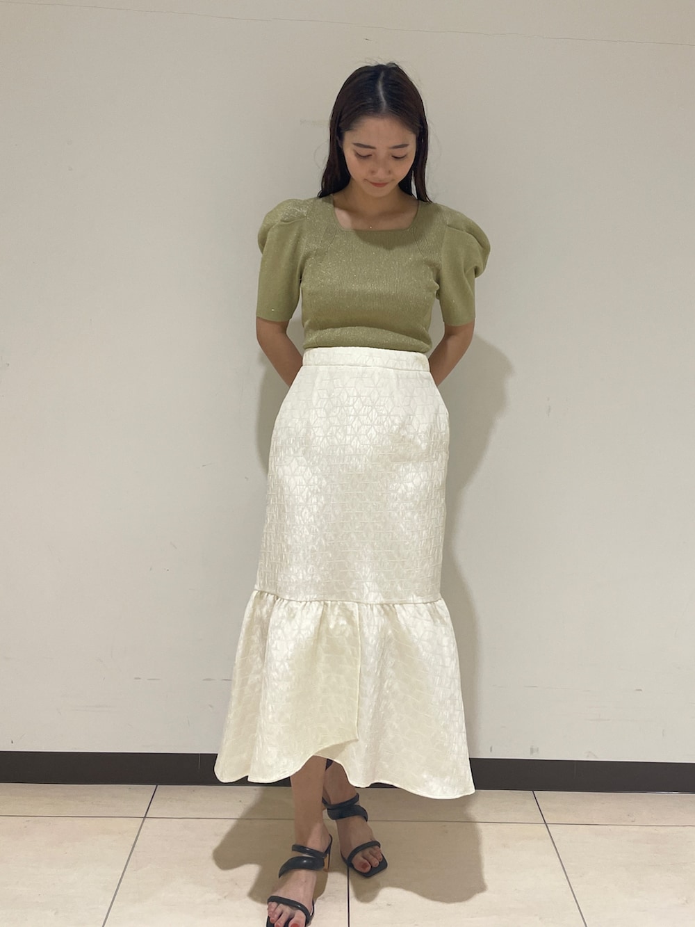 ホワイト系のスカート、グリーン系のニット/セーター、ブラック系のサンダルを着用したレディースの春コーディネートの4枚目の写真