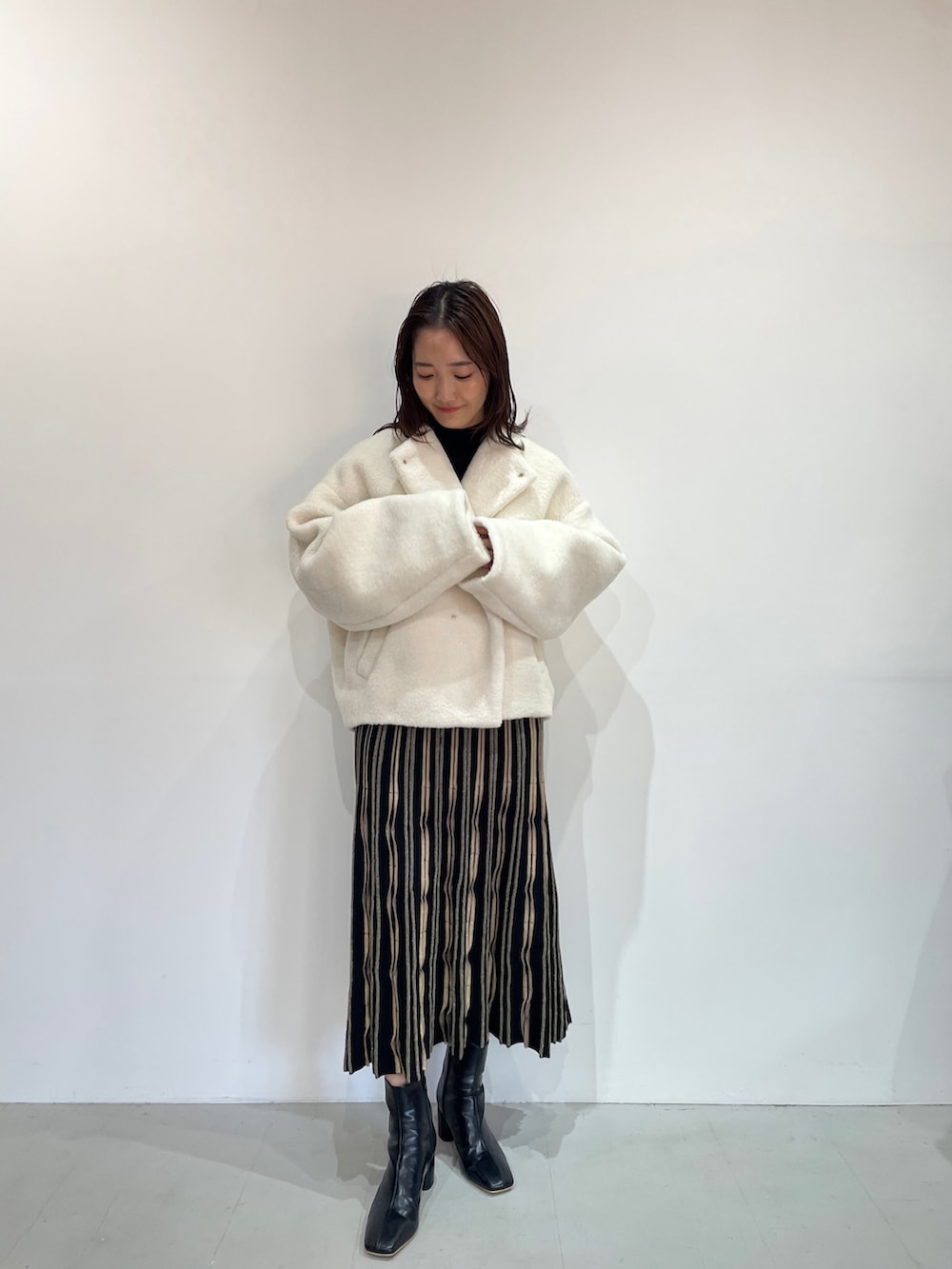 ベージュ系のサンダル、ホワイト系のブルゾン、ブラック系のワンピースを着用したレディースの秋コーディネートの2枚目の写真