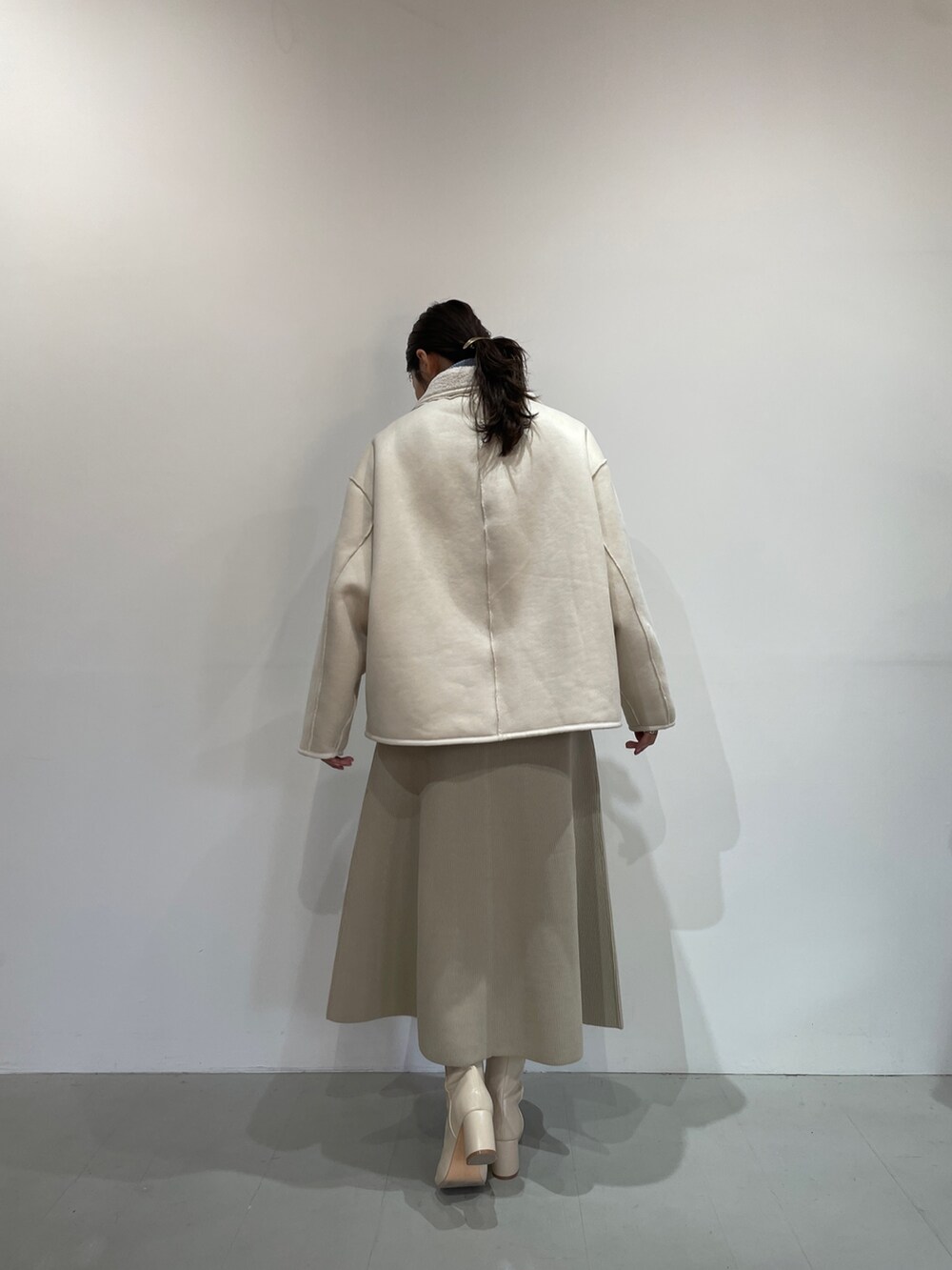 ブルー系のニット/セーター、ホワイト系のジャンパースカート、ホワイト系のブーツを着用したレディースの夏コーディネートの5枚目の写真