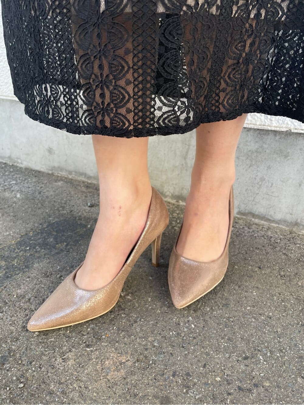 ゴールド系のパンプス、ゴールド系のクラッチバッグ、ブラック系のドレスを着用したレディースの冬コーディネートの8枚目の写真