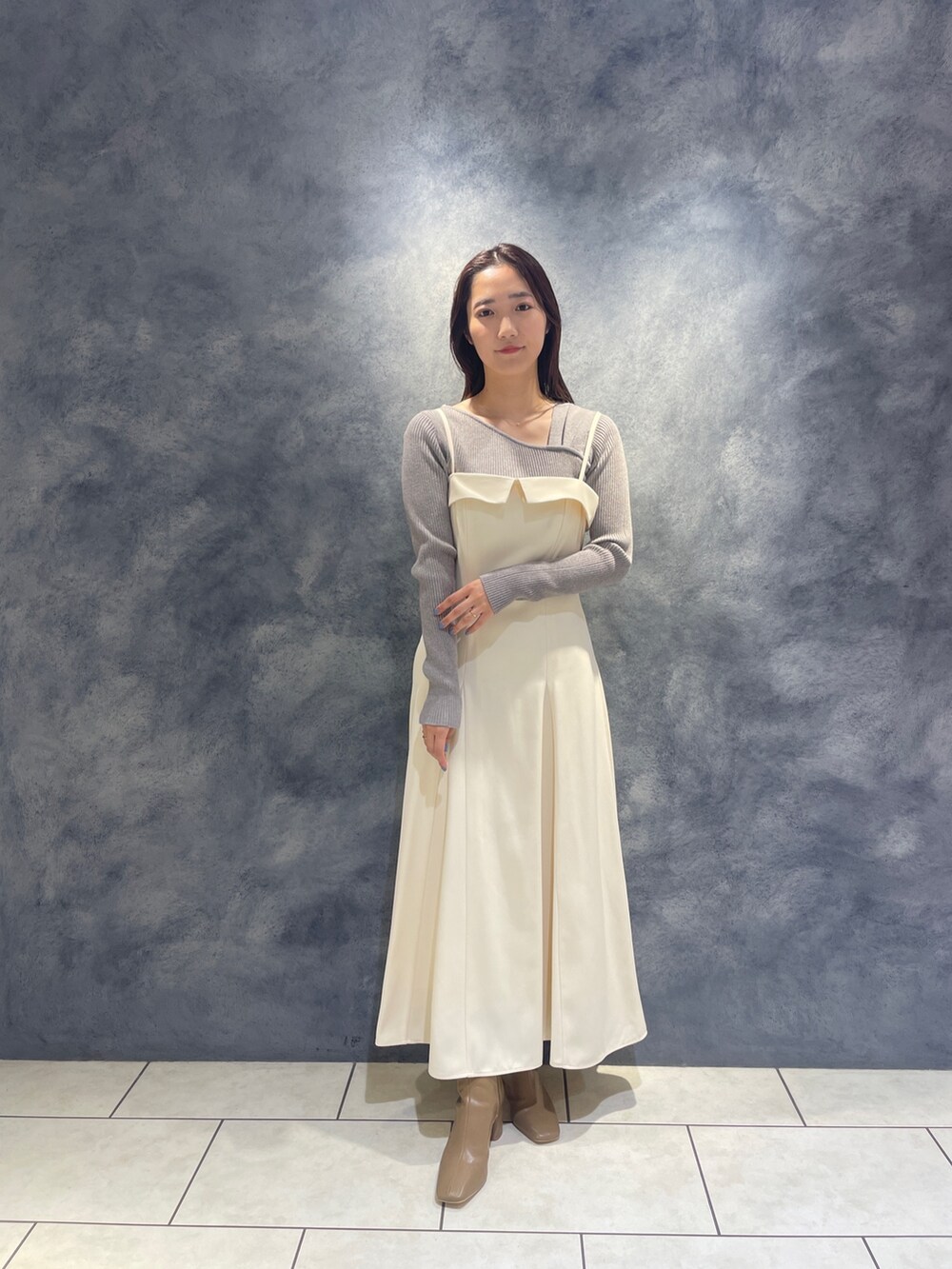 ベージュ系のブーツ、グレー系のニット/セーター、ホワイト系のワンピースを着用したレディースの秋コーディネートの3枚目の写真