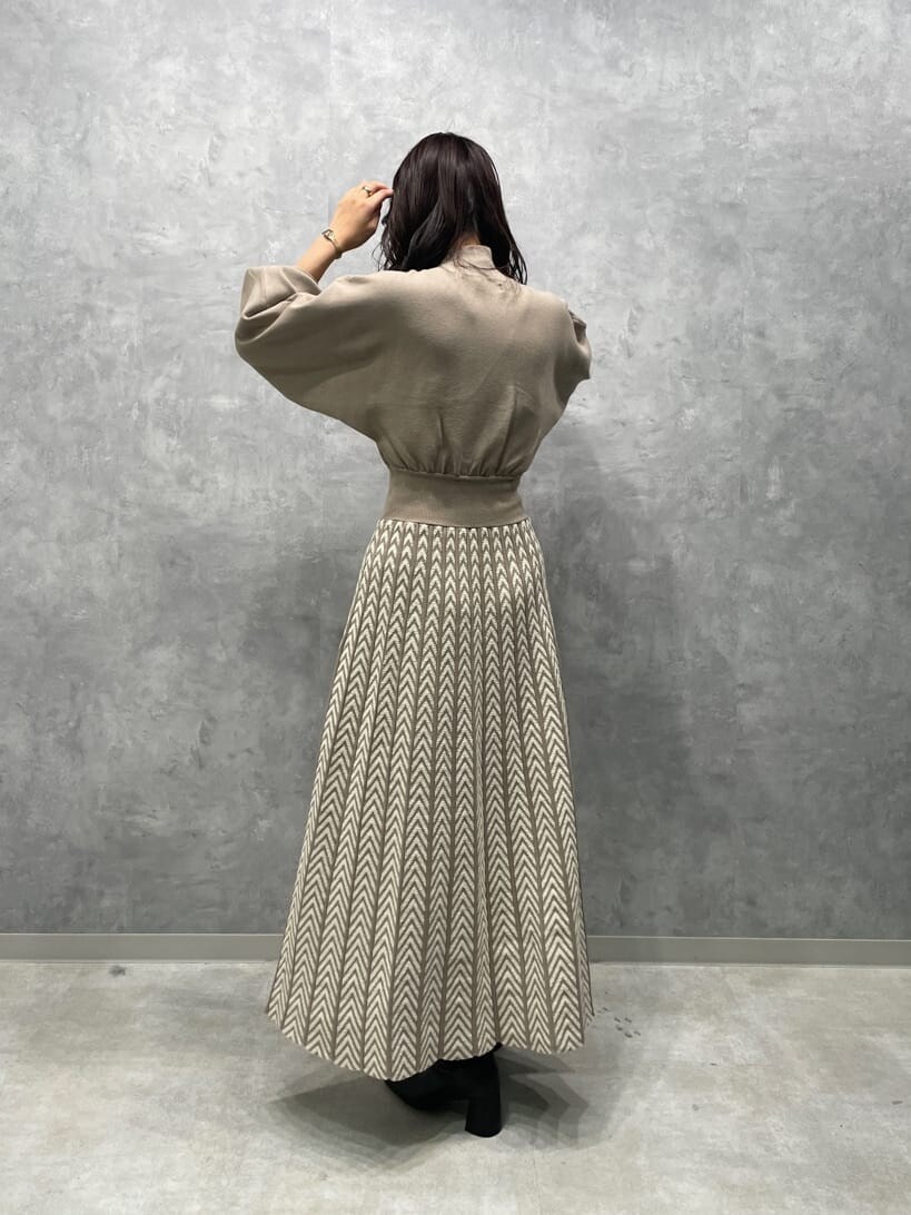 ホワイト系のノーカラーコート、ブラック系のブーツ、ベージュ系のワンピースを着用したレディースの秋コーディネートの6枚目の写真