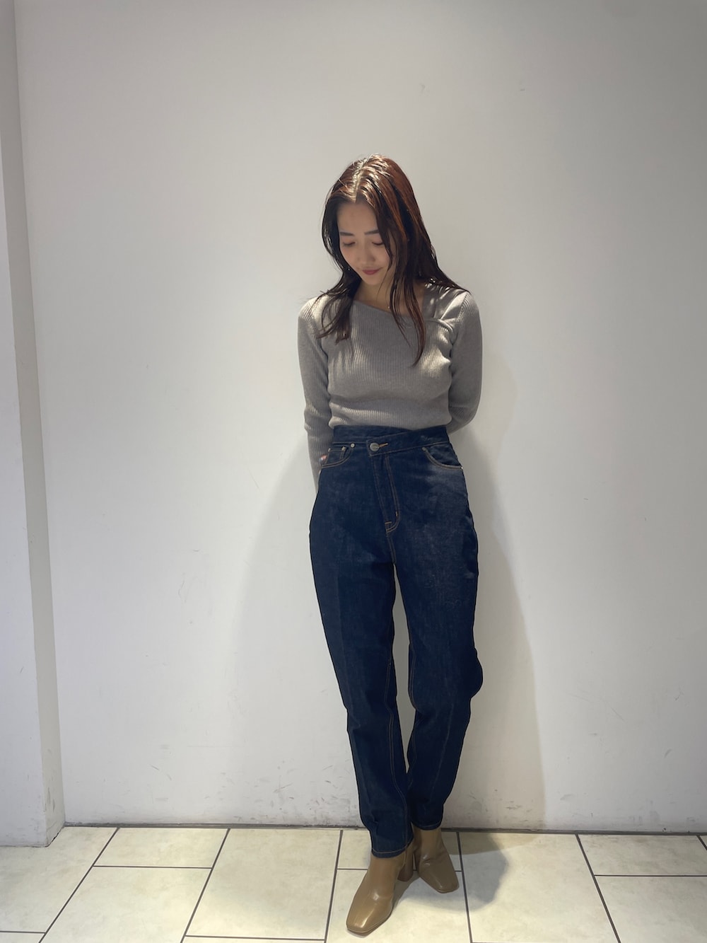 ホワイト系のノーカラーコート、グレー系のニット/セーター、ブルー系のデニムパンツを着用したレディースの秋コーディネートの5枚目の写真