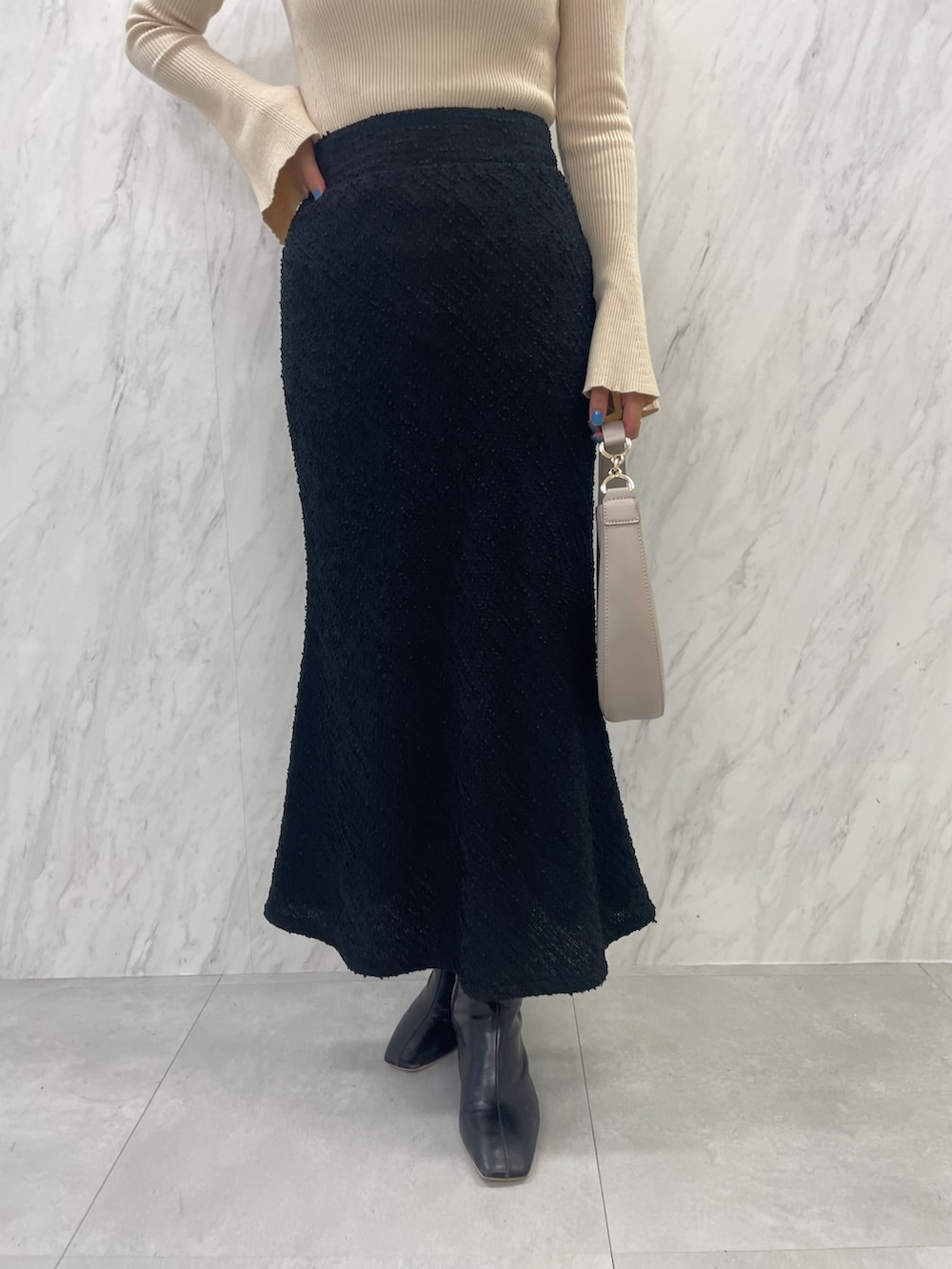 ブラック系のブーツ、ホワイト系のハンドバッグ、ブラック系のスカートを着用したレディースの秋コーディネートの10枚目の写真