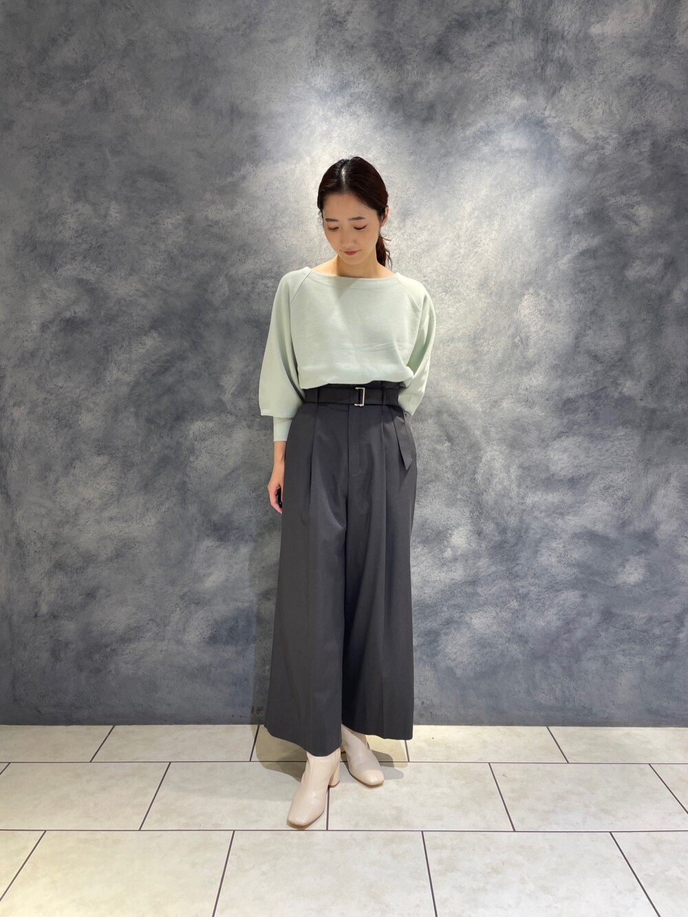 グレー系のその他パンツ、ホワイト系のブーツ、グリーン系のニット/セーターを着用したレディースの冬コーディネートの2枚目の写真