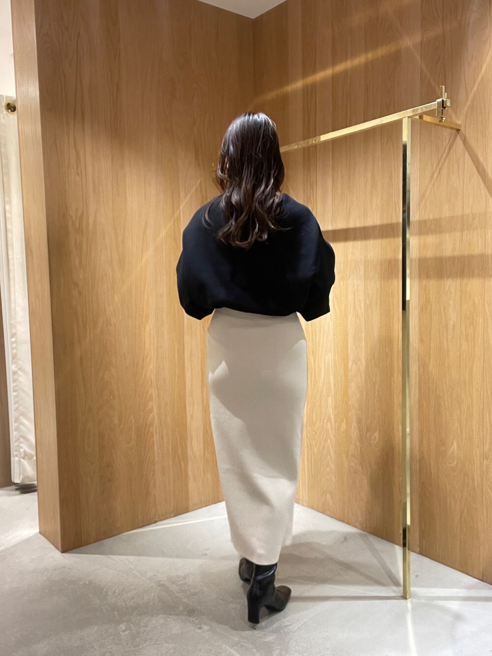 ホワイト系のスカート、ブラック系のニット/セーター、ブラック系のブーツを着用したレディースの秋コーディネートの5枚目の写真