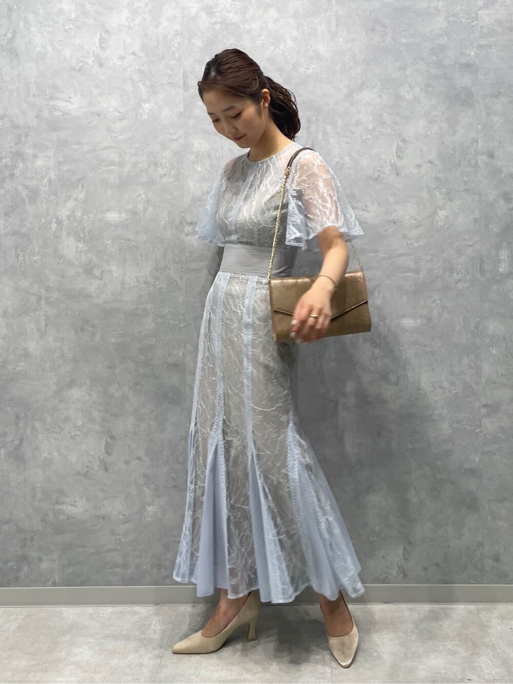 ゴールド系のクラッチバッグ、ベージュ系のパンプス、ブルー系のドレスを着用したレディースの春コーディネートの3枚目の写真