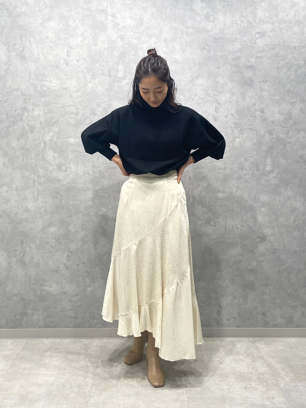 ブラック系のニット/セーター、ホワイト系のスカート、ベージュ系のブーツを着用したレディースの冬コーディネートの3枚目の写真