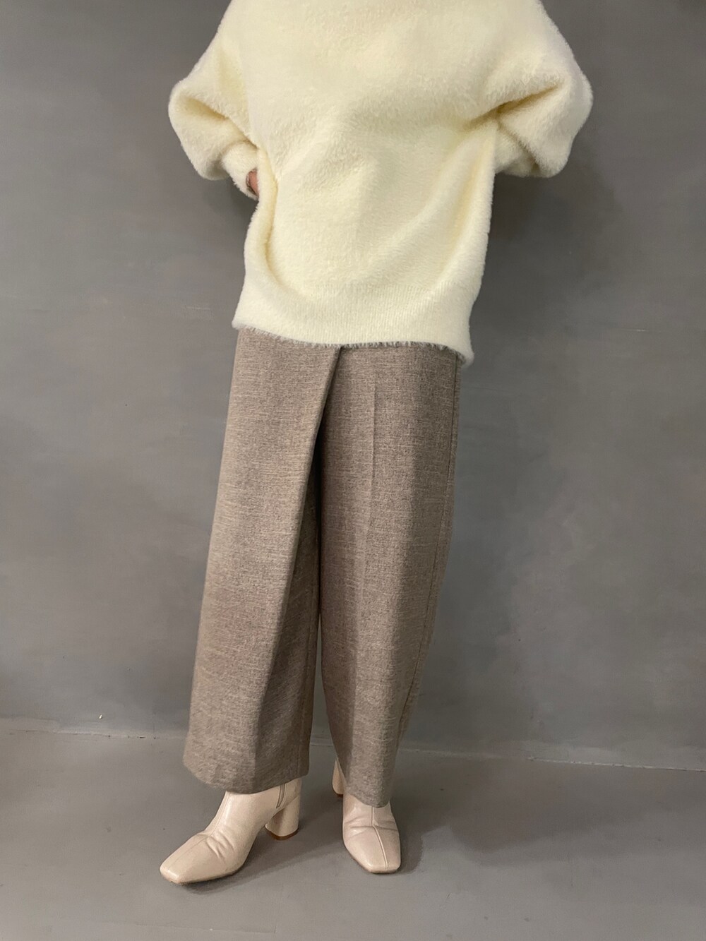 ホワイト系のニット/セーター、ベージュ系のその他パンツ、ホワイト系のブーツを着用したレディースの夏コーディネートの7枚目の写真