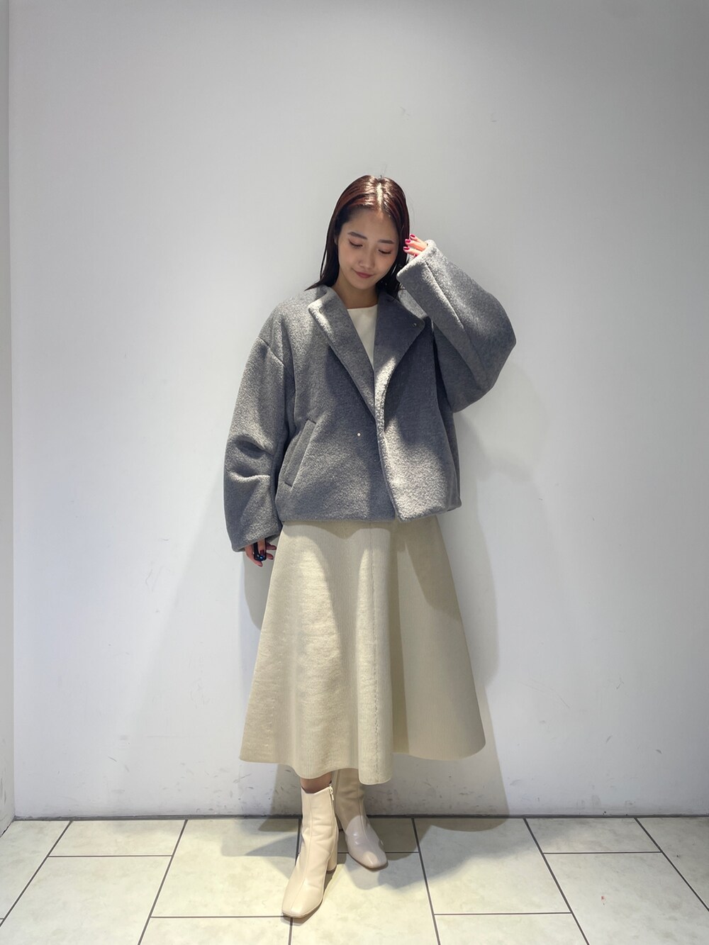 グレー系のブルゾン、ホワイト系のブーツ、ホワイト系のジャンパースカートを着用したレディースの秋コーディネートの2枚目の写真