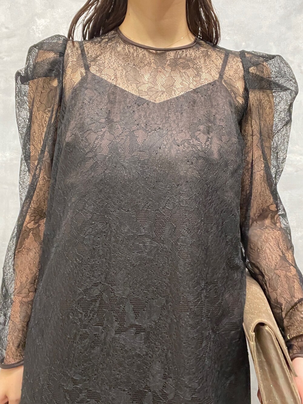 ゴールド系のパンプス、ゴールド系のハンドバッグ、ブラック系のドレスを着用したレディースの秋コーディネートの7枚目の写真