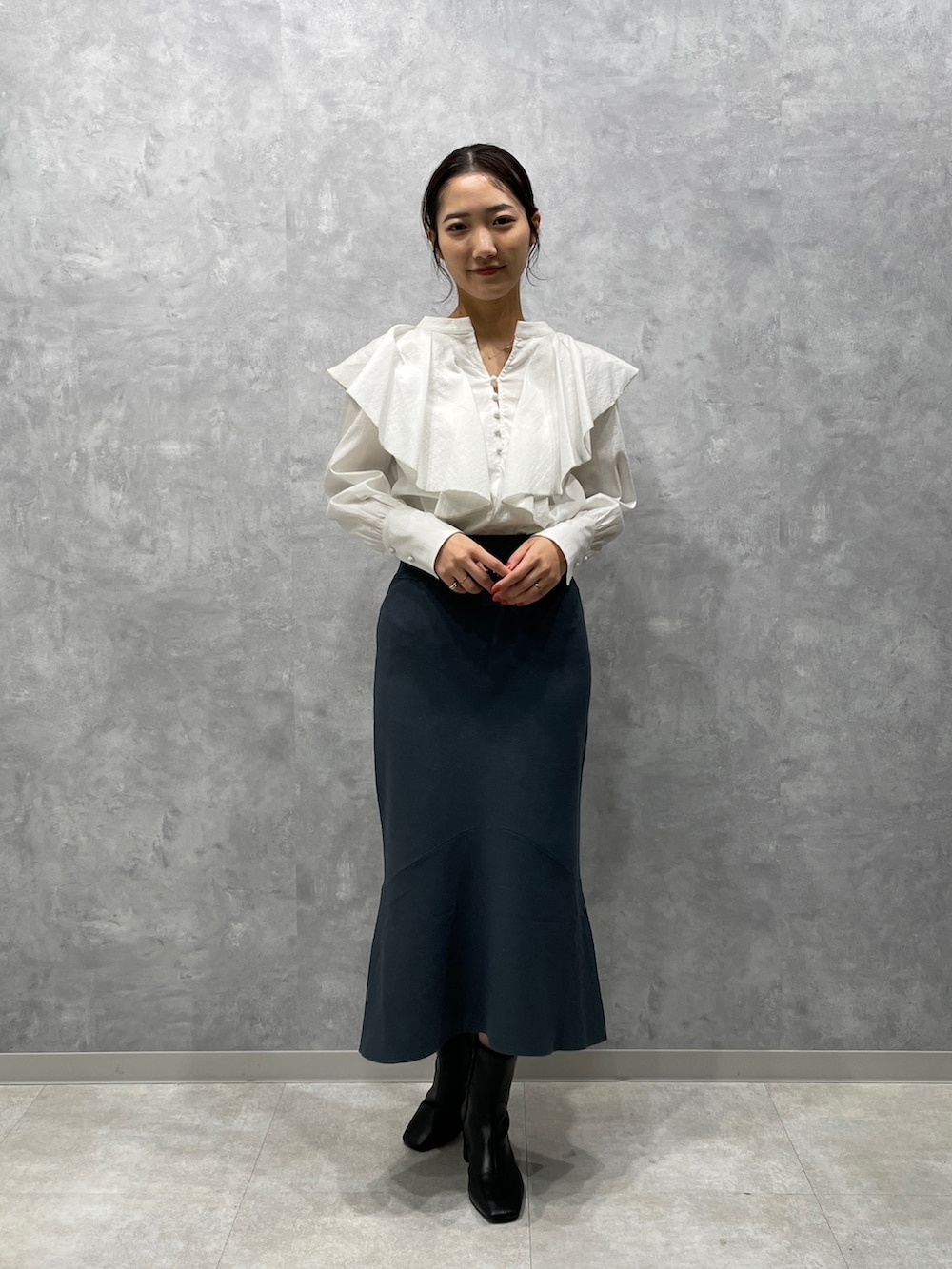 ホワイト系のカーディガン/ボレロ、ブラック系のブーツ、グリーン系のスカートを着用したレディースの冬コーディネートの4枚目の写真