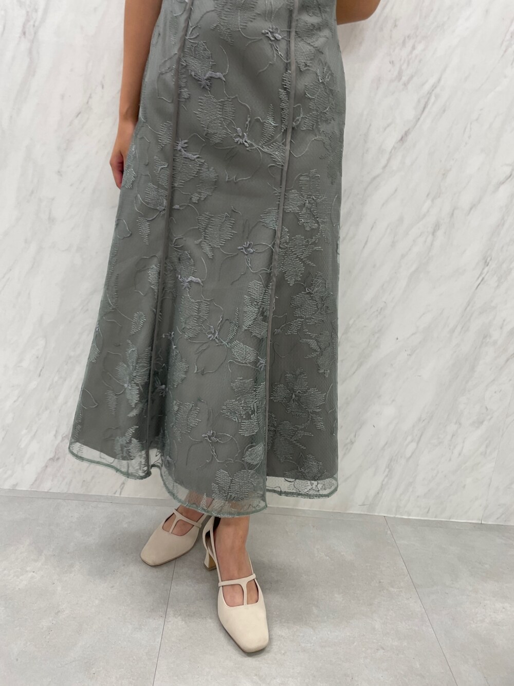 ホワイト系のパンプス、グリーン系のドレスを着用したレディースの冬コーディネートの7枚目の写真