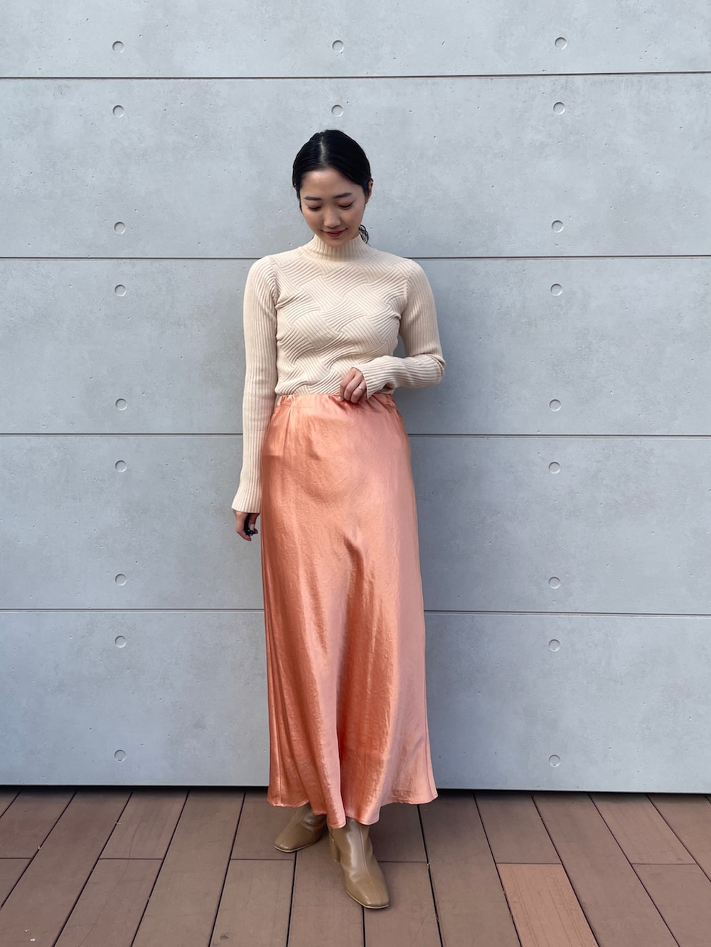 ホワイト系のニット/セーター、オレンジ系のスカート、ベージュ系のブーツを着用したレディースの冬コーディネートの3枚目の写真