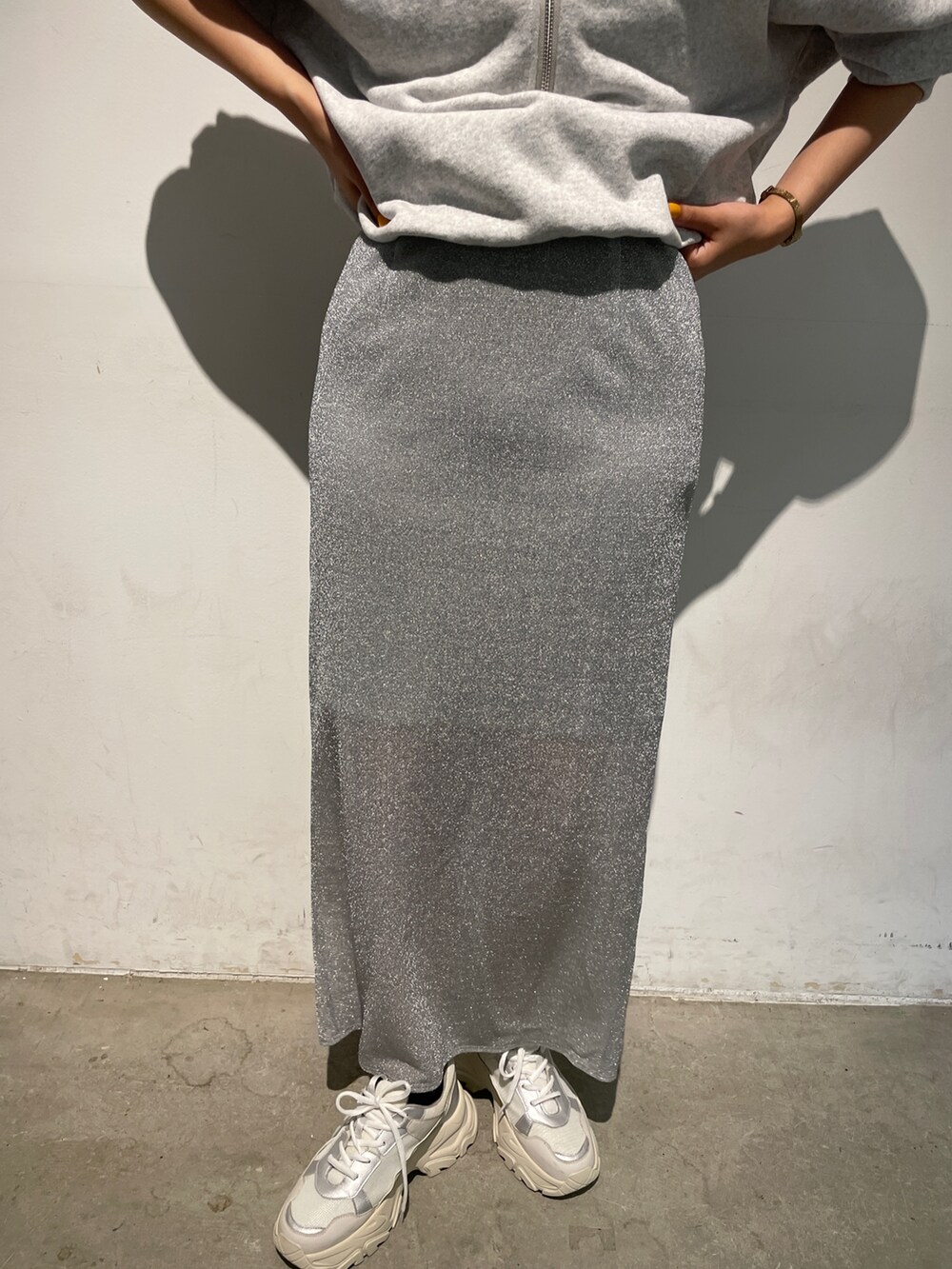 シルバー系のスカート、グレー系のスウェット、ホワイト系のスニーカーを着用したレディースの秋コーディネートの8枚目の写真