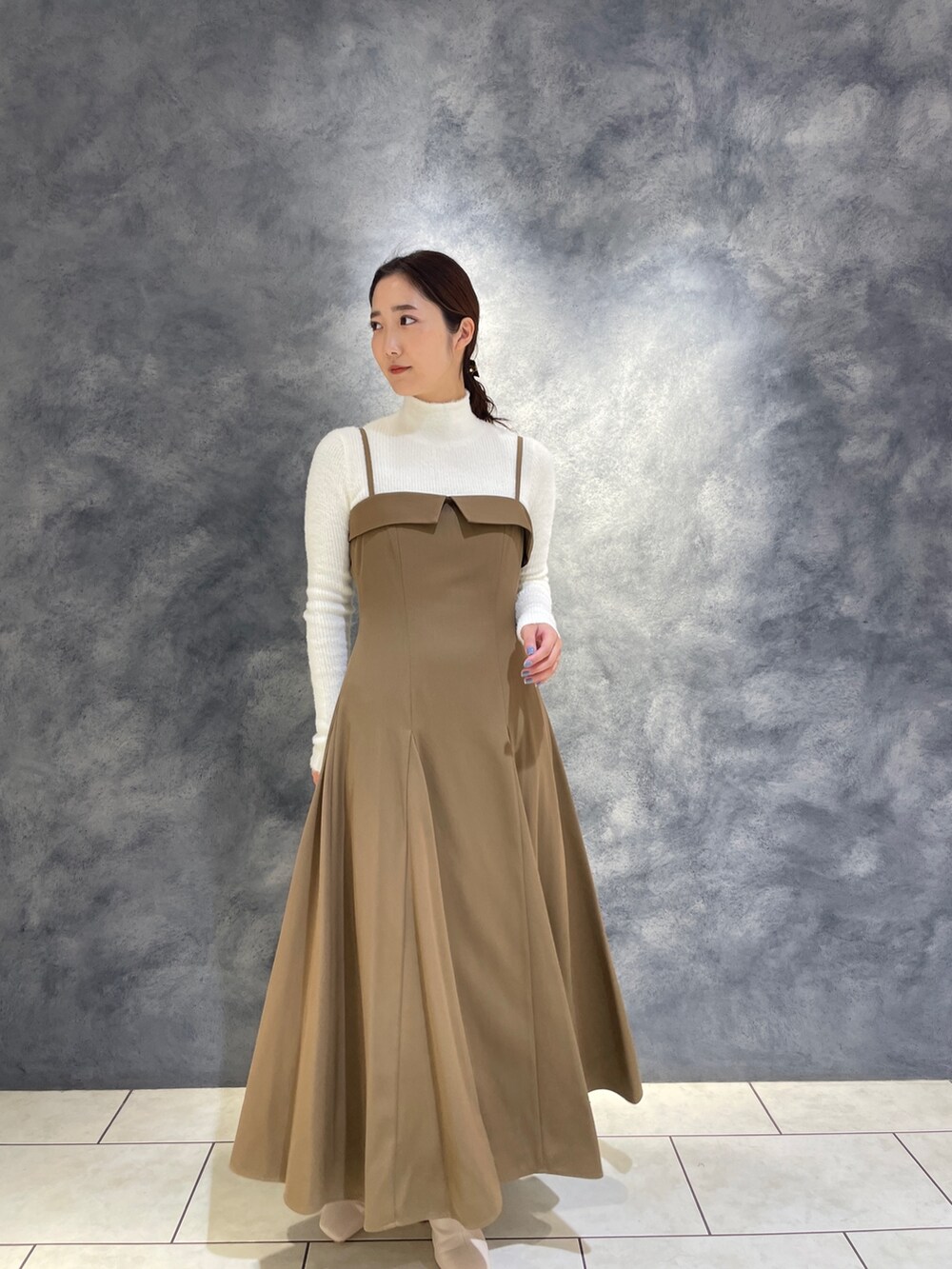 ベージュ系のワンピース、ホワイト系のニット/セーター、ホワイト系のブーツを着用したレディースの冬コーディネートの3枚目の写真