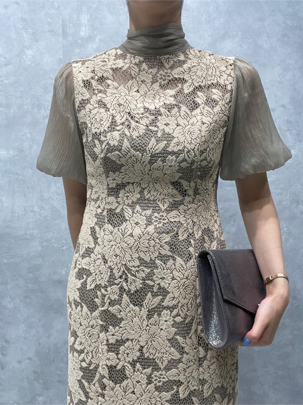 ベージュ系のドレス、シルバー系のパンプス、シルバー系のクラッチバッグを着用したレディースの夏コーディネートの5枚目の写真