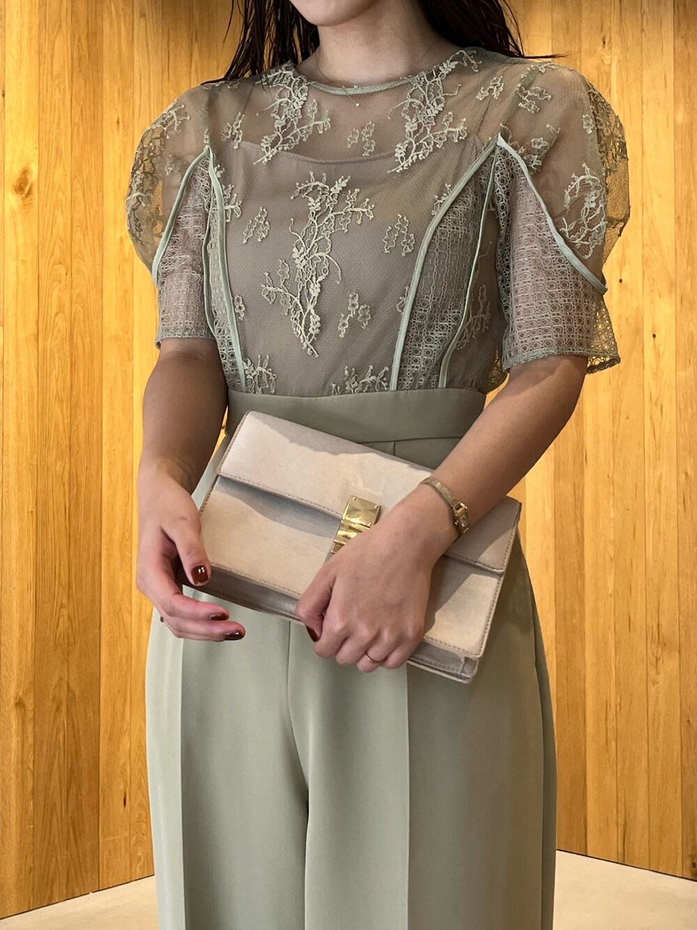 ベージュ系のパンプス、ベージュ系のクラッチバッグ、グリーン系のパンツドレスを着用したレディースの冬コーディネートの6枚目の写真