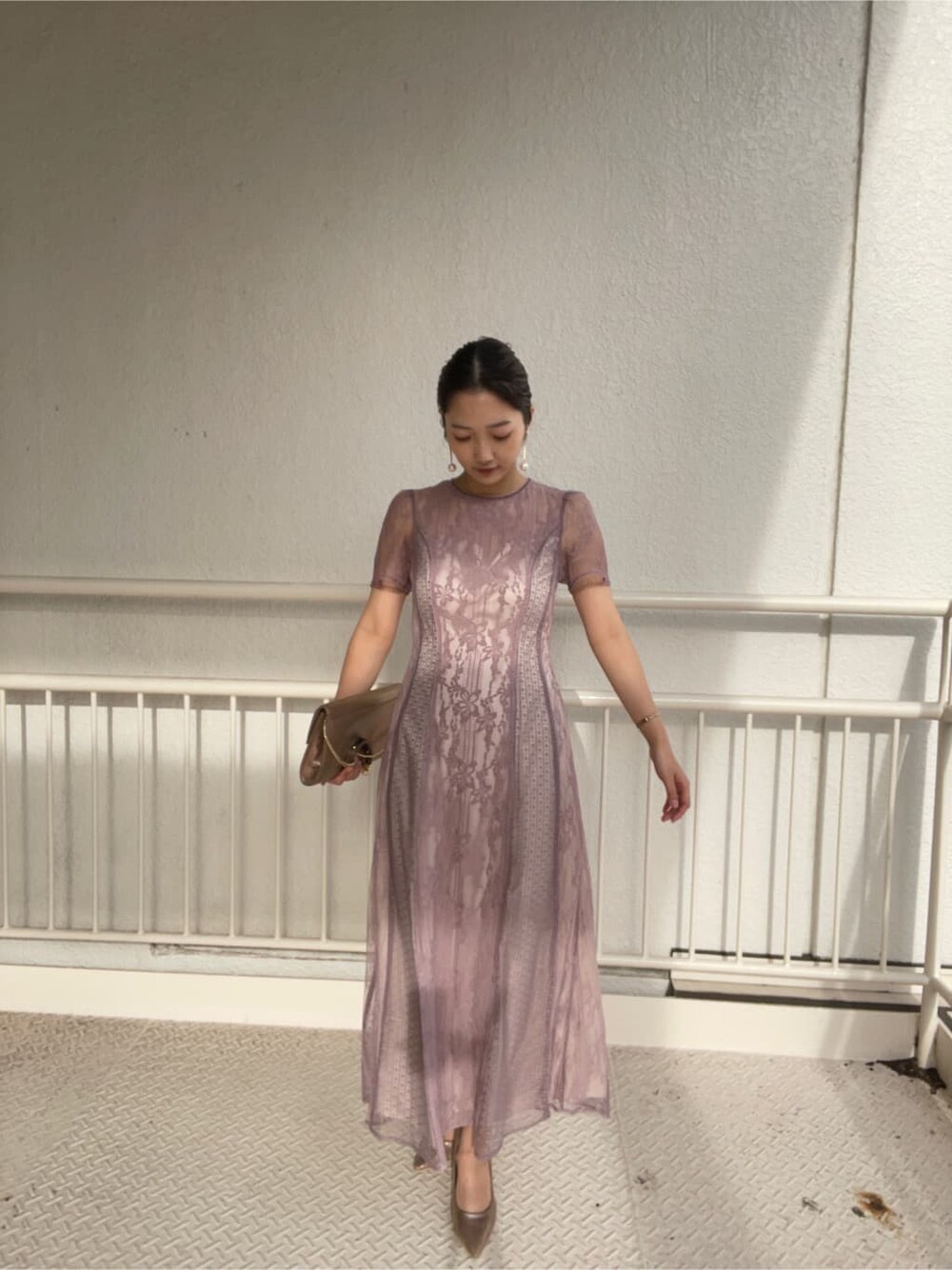 ゴールド系のパンプス、ゴールド系のクラッチバッグ、パープル系のドレスを着用したレディースの冬コーディネートの5枚目の写真
