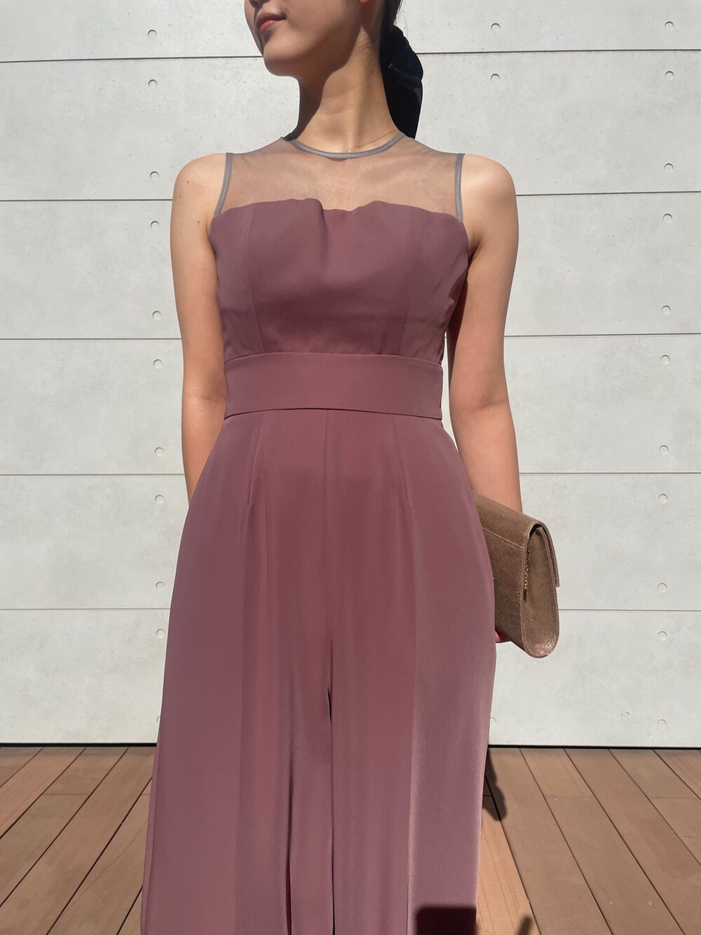 ピンク系のパンツドレス、ゴールド系のハンドバッグ、ベージュ系のパンプスを着用したレディースの秋コーディネートの7枚目の写真