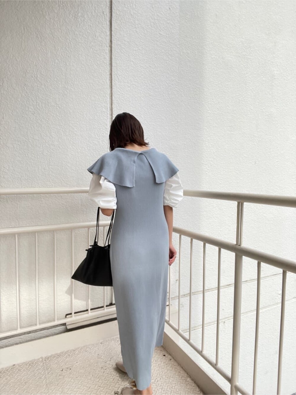 ブルー系のワンピース、ブラック系のハンドバッグ、ホワイト系のパンプスを着用したレディースの冬コーディネートの8枚目の写真