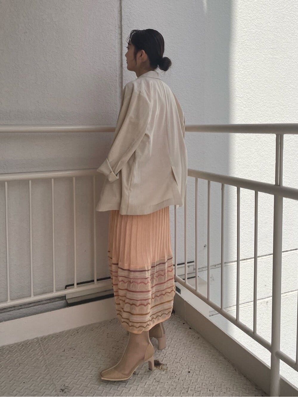 ベージュ系のブーツ、ベージュ系のテーラードジャケット、オレンジ系のワンピースを着用したレディースの春コーディネートの3枚目の写真