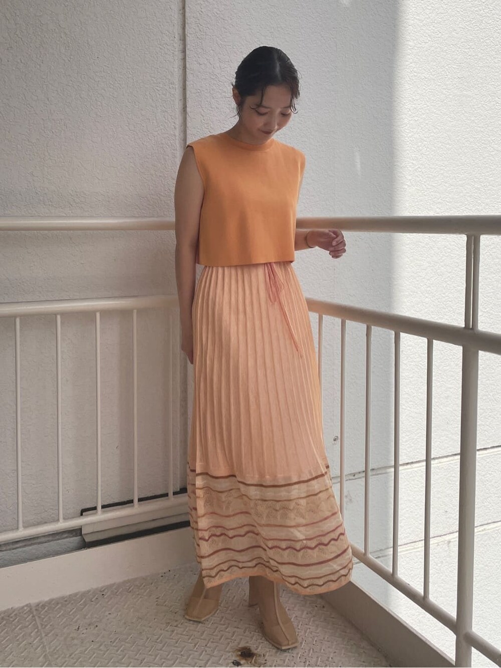 ベージュ系のブーツ、ベージュ系のテーラードジャケット、オレンジ系のワンピースを着用したレディースの春コーディネートの5枚目の写真