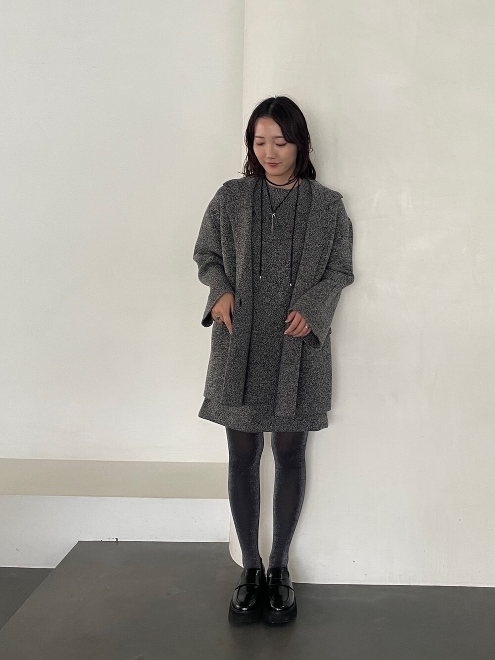 グレー系のワンピース、ブラック系のローファー、グレー系のテーラードジャケットを着用したレディースの冬コーディネートの3枚目の写真