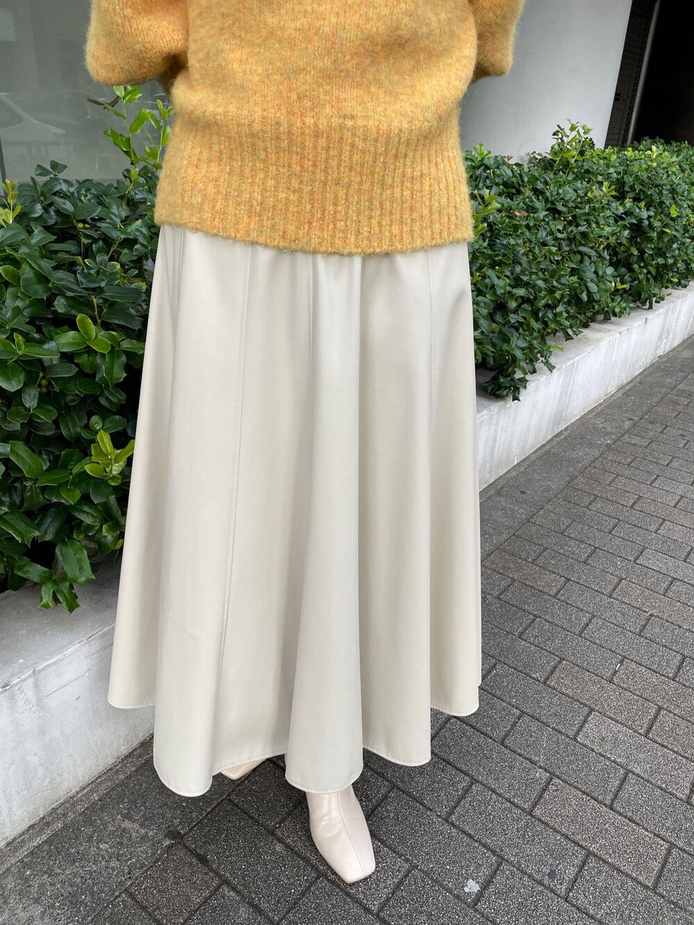 ホワイト系のブーツ、ホワイト系のスカート、イエロー系のニット/セーターを着用したレディースの秋コーディネートの6枚目の写真