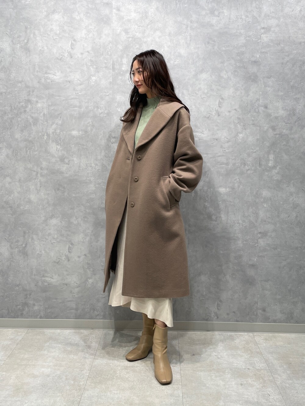 ベージュ系のブーツ、グリーン系のニット/セーター、ベージュ系のその他アウターを着用したレディースの冬コーディネートの2枚目の写真