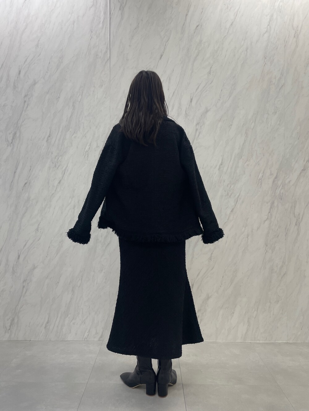 ブラック系のブーツ、ホワイト系のハンドバッグ、ブラック系のスカートを着用したレディースの秋コーディネートの5枚目の写真