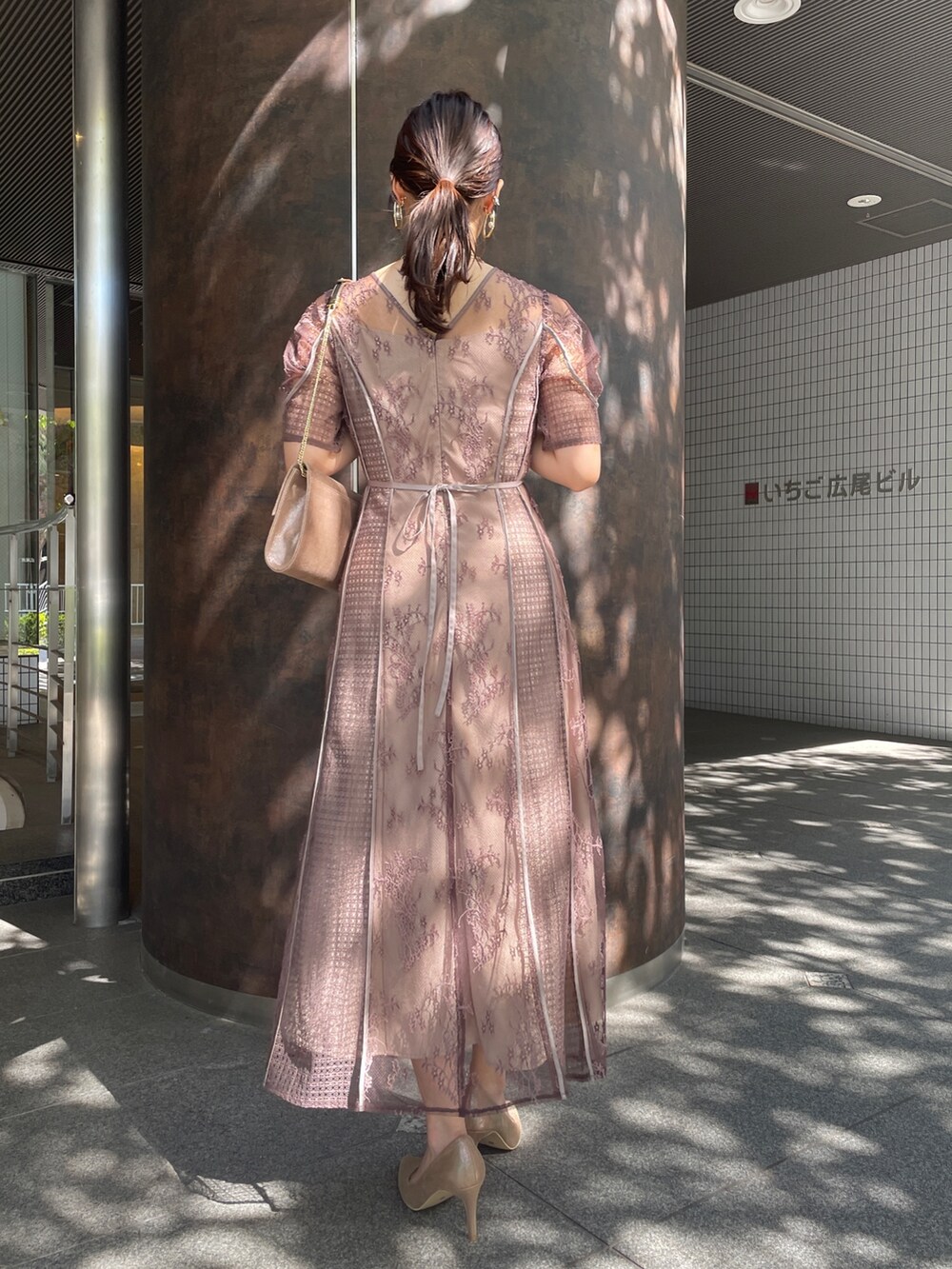 ベージュ系のドレス、ブラック系のノーカラーコート、ゴールド系のハンドバッグを着用したレディースの秋コーディネートの10枚目の写真