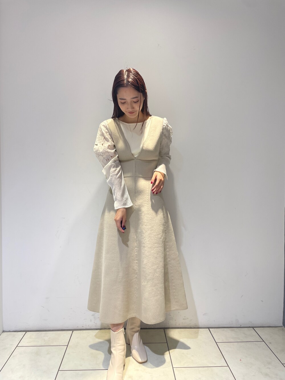 グレー系のブルゾン、ホワイト系のブーツ、ホワイト系のジャンパースカートを着用したレディースの秋コーディネートの7枚目の写真